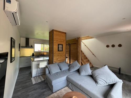 un salon avec un canapé et une cuisine dans l'établissement Duplex le Red Cedar avec terrasse et jardin, à Gérardmer