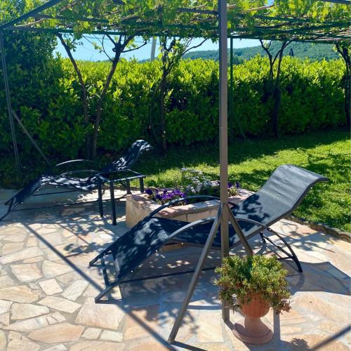 a patio with a table and chairs under an umbrella at Casa Vacanze Podere San Giusto Volterra in Volterra