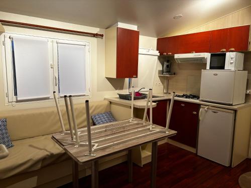 uma pequena cozinha com uma mesa e um frigorífico em camping Capbreton lapointe em Capbreton