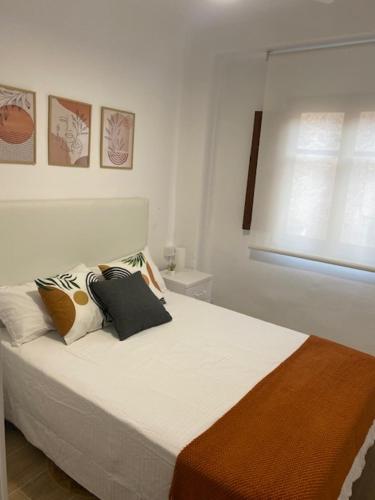 Un dormitorio con una cama blanca con almohadas y una ventana en La Casa del Castell, en Onda