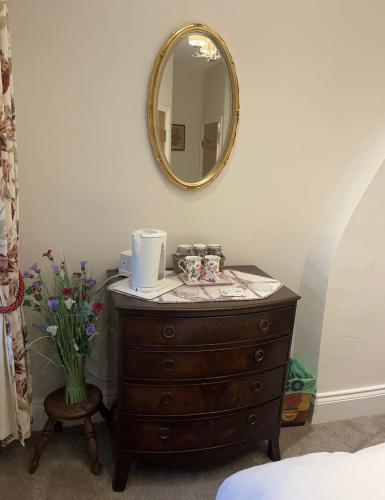 a dresser with a mirror and a vase of flowers at Picket Post House Bed & Breakfast in Catterall