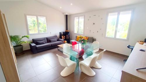 Appartement Pinede Man Yelle في ساناري سور مير: غرفة معيشة مع طاولة زجاجية وكراسي بيضاء