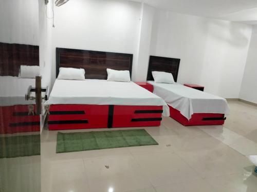ブリンダーバンにあるPavan Guest Innのベッドルーム1室(白と赤の家具、ベッド2台付)