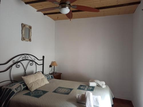 - une chambre avec un lit et un ventilateur de plafond dans l'établissement Casita de Campo El Bujeo, à Grenade