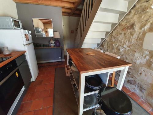 La cuisine est équipée d'une table, d'un réfrigérateur et d'une cuisinière. dans l'établissement Maison de campagne, à Saint-Saturnin-sur-Loire