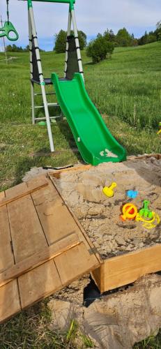 einen Spielplatz mit grüner Rutsche und Spielzeug in der Unterkunft Nad Cicha in Ujsoły
