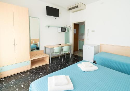 a bedroom with two beds and a desk with a television at Residence Rex in Chioggia