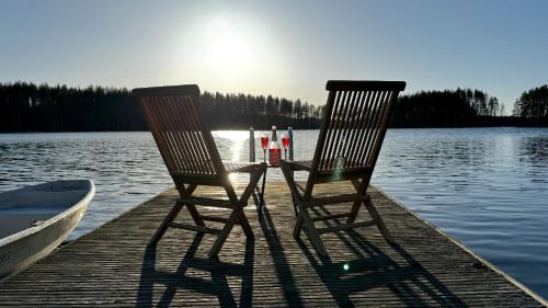 two chairs sitting on a dock next to a boat at Villa Kolovesi - Saimaa Retreat in Savonlinna