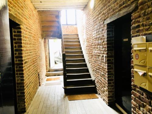 a brick hallway with a staircase in a building at La Petite Rhonelle - Studio en hypercentre in Valenciennes