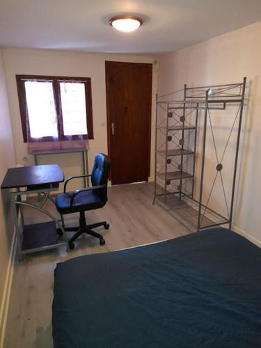 une chambre avec un lit, un bureau et une chaise dans l'établissement Jolie longère au calme proche du Futuroscope, à Saint-Georges-lès-Baillargeaux