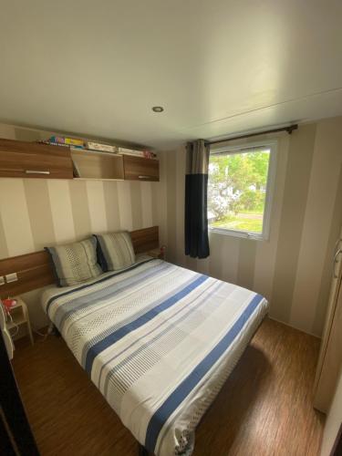 - une chambre avec un grand lit et une fenêtre dans l'établissement Camping à la Cotinière-Piscine-Bungalow cosy entre Océan et Pinède, à La Cotinière