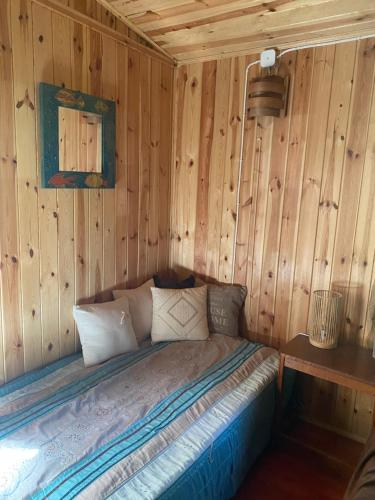 1 dormitorio con 1 cama en una pared de madera en Przytulny domek w lesie blisko rzeki en Ryczywół