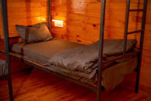 a bunk bed in a room with wooden walls at Odin Hostel Jibhi in Jibhi
