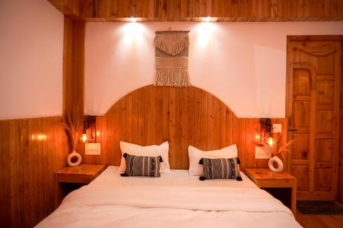 a bedroom with a bed and a dress hanging on the wall at Odin Hostel Jibhi in Jibhi