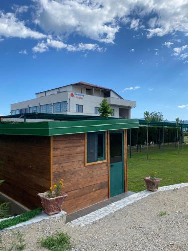 um pequeno edifício com uma porta verde num campo em Hostel Internacional em Grilë