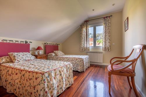 a bedroom with two beds and a chair at Casa entre Santander y Cabárceno con piscina in Revilla de Camargo