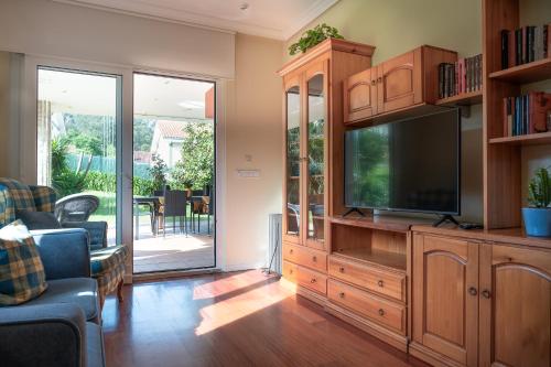 a living room with a large entertainment center with a flat screen tv at Villa entre Santander y Cabárceno con piscina in Revilla de Camargo