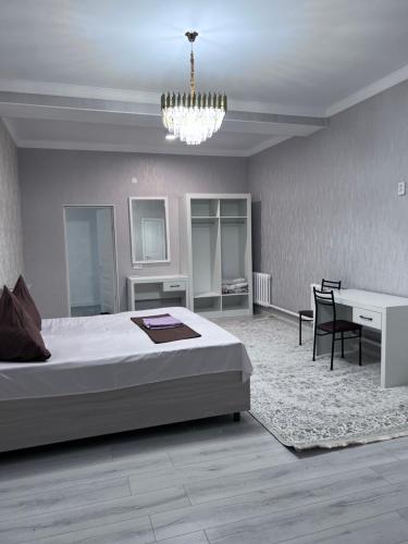 a bedroom with a bed and a desk and a chandelier at Гостиница NUR in Aralʼsk