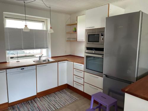 La cuisine est équipée de placards blancs et d'un réfrigérateur en acier inoxydable. dans l'établissement Nice and Cozy family house at Billund Center, à Billund