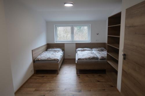 two beds in a room with a window at Wellness chata Kouty in Loučná nad Desnou