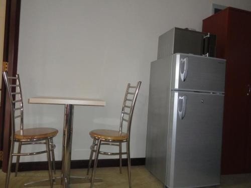 a table and two chairs next to a refrigerator at City And Hills View Apartment in Nuwara Eliya