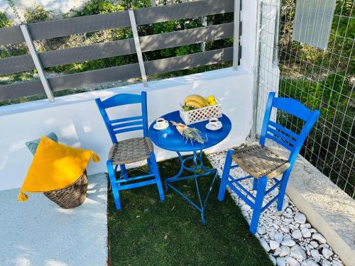 two blue chairs and a table with a basket of fruit at Astre&Jeanne suites in Sozopoli