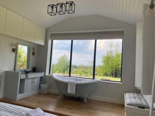 a large bathroom with a tub and a large window at Harry's Cottage in Aghanloo