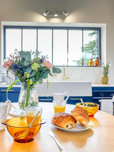 a table with a plate of croissants and a vase of flowers at Charmante girondine avec jardin, proche St-Émilion in Libourne