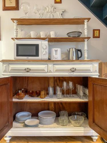 a microwave sitting on top of a shelf with dishes at Charmante girondine avec jardin, proche St-Émilion in Libourne