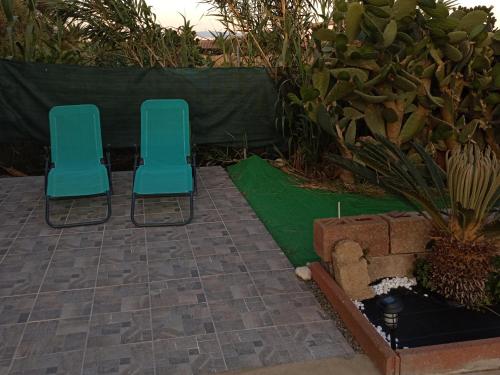 two blue chairs sitting on a patio with green grass at Casa vacanza Ligustro appartamento il gabbiano in SantʼAntìoco