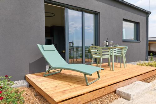 a wooden deck with a green chair and a table at Apartments Vineyard19 in Retz