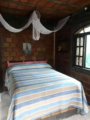 a bedroom with a bed with a blue and white striped blanket at Pousada do Oasis in Morretes