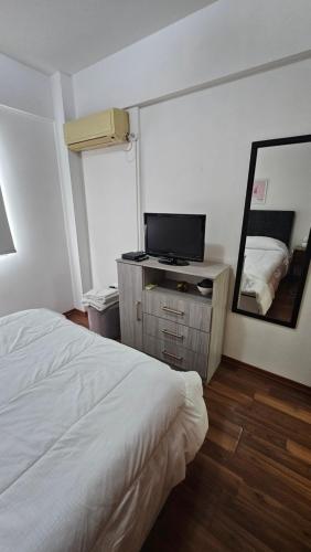 um quarto com uma cama branca e um espelho em Acogedor departamento 1 dormitorio em El Palomar