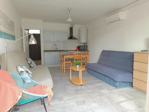 un salon avec un canapé bleu et une cuisine dans l'établissement Studio Palavas proche plages et centre - terrasse - Clim & Parking, à Palavas-les-Flots