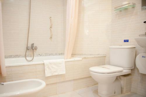 a white toilet sitting next to a bath tub at Hotel Arha Santander in Santander