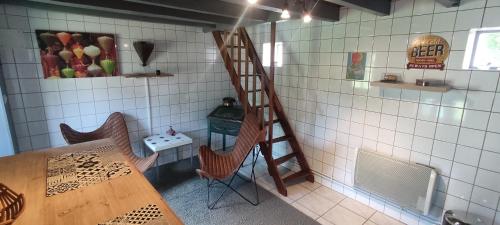 une cuisine avec une table, des chaises et une échelle dans l'établissement La Chaume de Condé, à La Celle-Condé