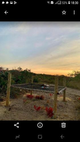 a fence with a bunch of red flowers behind it at Pousada Cabanas in Alto Paraíso de Goiás