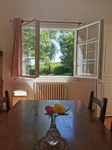 - une table à manger avec un vase orné de fleurs dans l'établissement Maison de Campagne & Spa 6 pers 15 min d'Auch, à Sainte-Christie