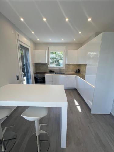 a white kitchen with a white table and stool at Villa Thalia in Kavala