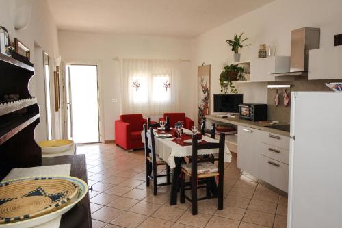 een keuken en een woonkamer met een tafel en stoelen bij Villaggio polifemo 38 Località Cala Sapone in Cala Sapone