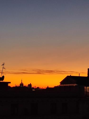 an orange sunset with the silhouette of a city at Rooftop Terrace - elegante attico con idromassaggio in Milan