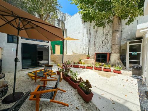 patio z ławkami, parasolem i roślinami w obiekcie Casa vishami w mieście Cozumel