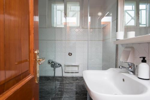 y baño blanco con lavabo y ducha. en Villa Christina, en Katsíngrion