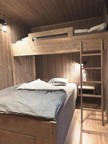 a bedroom with two bunk beds in a wooden wall at Snowcake Cottage in Sør-Fron