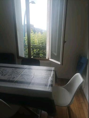 un ordinateur portable assis sur une table devant une fenêtre dans l'établissement Appartement cosy, à Choisy-le-Roi