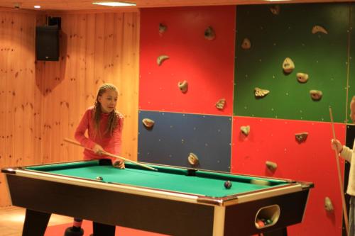 a young girl playing pool in a room at Rauland Høgfjellshotell in Rauland