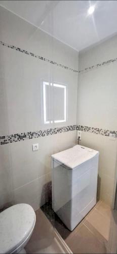 une salle de bain blanche avec toilettes et fenêtre dans l'établissement Villa Châteauneuf Jardin Biovès, à Menton