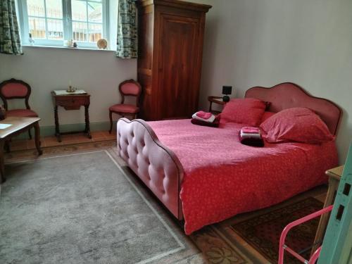 Maison d'hôtes في Orchaise: غرفة نوم مع سرير وردي مع وسائد حمراء