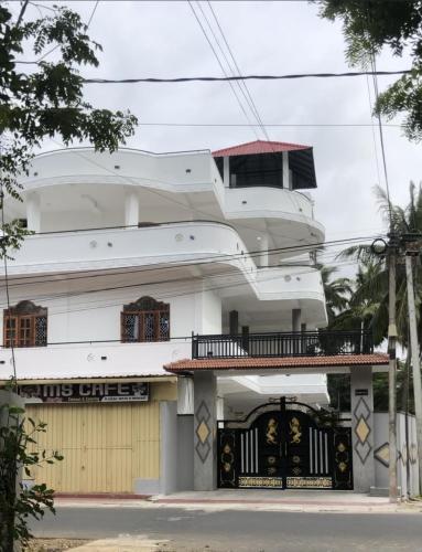 a large white house with a balcony and a gate at SARMA VILLA in Tirunelveli East