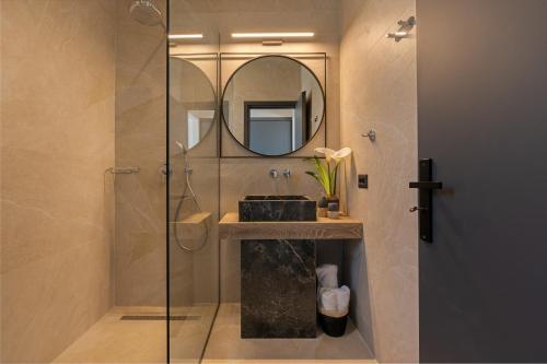 a bathroom with a shower with a sink and a mirror at Luxury Stone Villas Kefalonia in Trapezaki